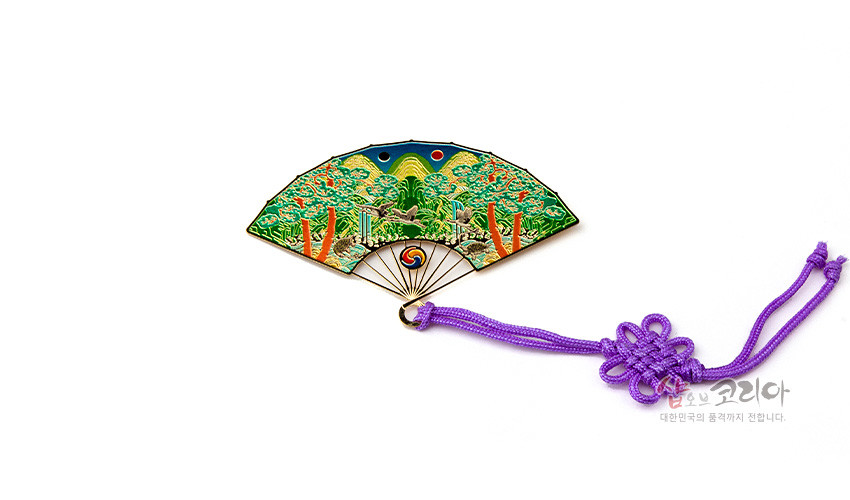 [텍스트: 샵오브코리아 대한민국의 품격까지 전합니다.] 금속 재질 부채 모양 책갈피, 칠보 기법으로 오봉도와 태극 문양을 화려한 녹색·적색·청색으로 표현, 보라색 전통 매듭 끈 장식 이미지 설명