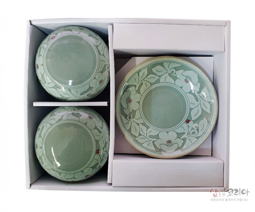 [텍스트: 샵오브코리아 대한민국의 품격까지 전합니다.] 연한 비취색 청자 도자기 위 무궁화와 잎사귀 문양을 투각 기법으로 둘레에 장식한 2인 다기세트 구성 이미지 설명