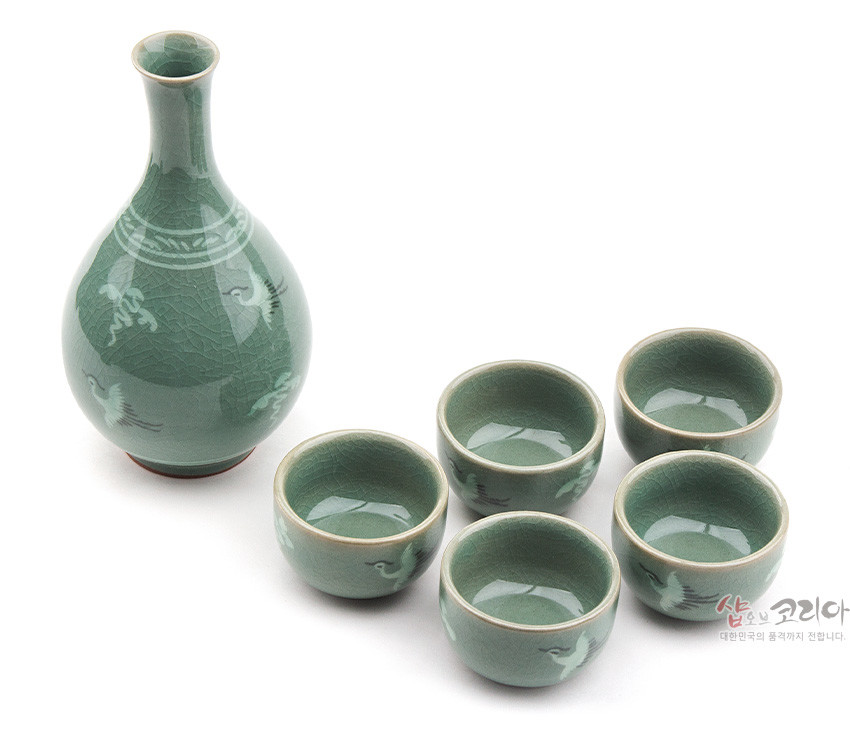 [텍스트: 샵오브코리아 대한민국의 품격까지 전합니다] 비취색 유약과 빙렬 기법이 어우러진 청자 주병과 술잔 세트, 학과 구름 상감 문양이 특징인 전통 주기 구성