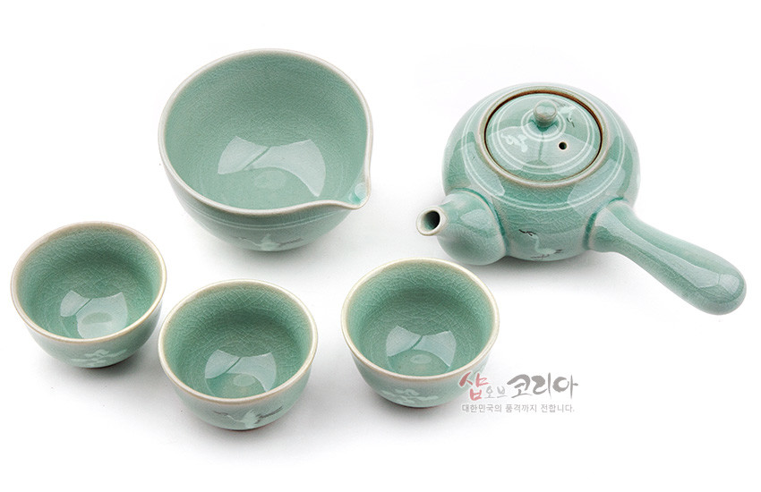 [텍스트: 샵오브코리아 대한민국의 품격까지 전합니다.] 옅은 비취색 유약의 청자 재질, 운학 문양과 잔잔한 균열무늬가 어우러진 옆손잡이 주전자·숙우·찻잔 3점 구성 다기세트 이미지 설명