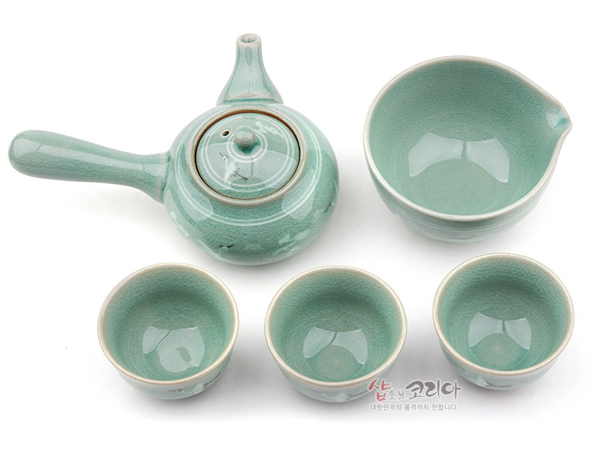 [텍스트: 샵오브코리아 대한민국의 품격까지 전합니다.] 옆손잡이 주전자와 숙우, 찻잔 3점으로 구성된 비취색 청자 다기세트, 균열유와 은은한 운학문양이 돋보이는 전통 도자기 디자인