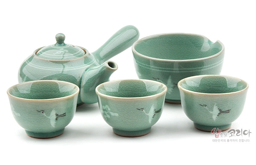 [텍스트: 샵오브코리아 대한민국의 품격까지 전합니다.] 비취색 청자 재질, 균열유 약 문양과 옆손잡이 주전자·숙우·잔 3점 구성, 운학 문양이 은은하게 새겨진 3인다기세트 이미지 설명