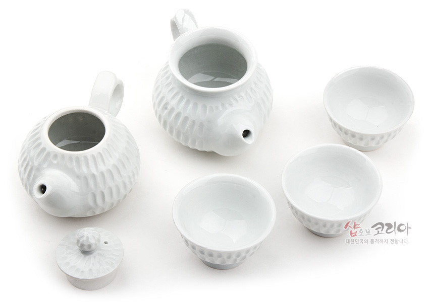 [텍스트: 샵오브코리아 대한민국의 품격까지 전합니다.] 백자 재질의 순백색 다관과 찻잔에 규칙적인 빗살무늬 양각과 음각을 더한 3인 다기 세트 구성