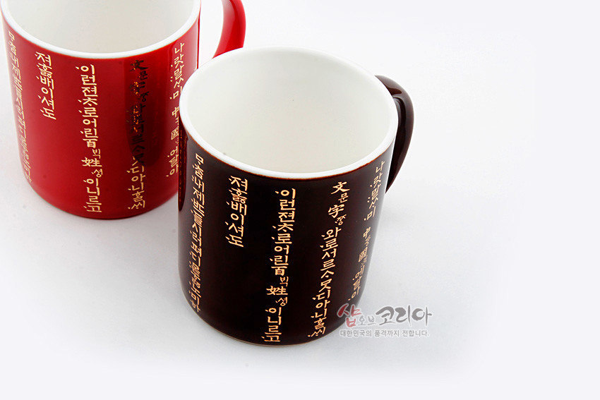 [텍스트: 나랏말ᄊᆞ미 듕귁에 달아 문ᄍᆞ와로 서로 사맛디 아니할쎄 이런 젼차로 어린 백셩이 니르고져 할ᄲᅡ야 마참내 제 뜨들 시러펴디 몯ᄒᆞᄂᆞ니라] 붉은색·갈색 유약 도자 머그컵에 황금빛 훈민정음 언해 세로 배치 디자인