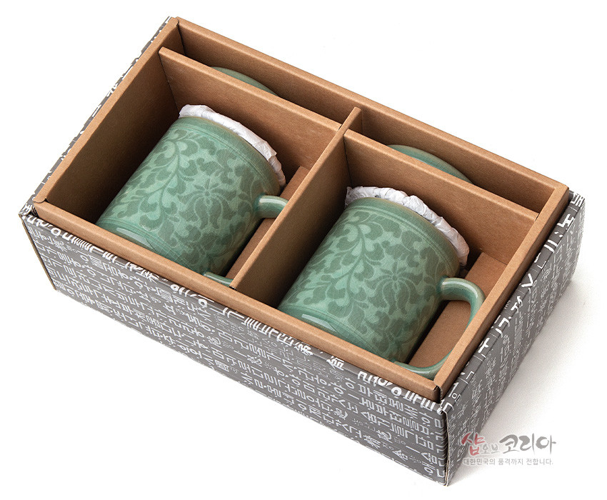 [텍스트: 샵오브코리아 대한민국의 품격까지 전합니다.] 한글 패턴 상자에 담긴 연녹색 청자 머그 2인 세트, 목단당초 문양이 은은하게 새겨진 도자기 질감 연출