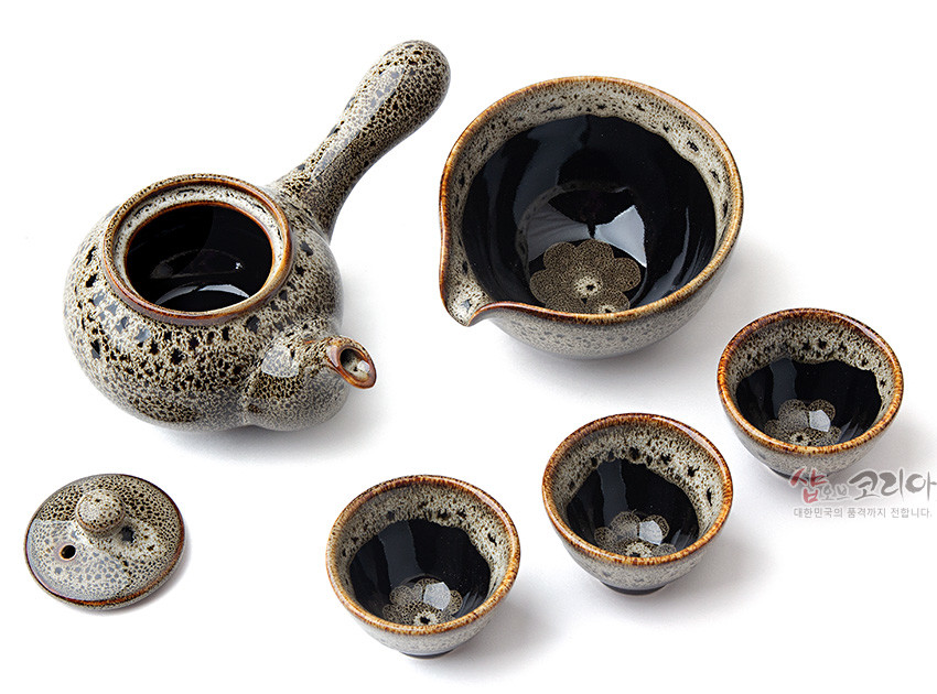 [텍스트: 샵오브코리아 대한민국의 품격까지 전합니다.] 흑유 바탕 위 회갈색 거품무늬 천목기법 도자, 주전자·숙우·찻잔에 갈색 테두리와 내면 꽃문양이 어우러진 3인다기세트 이미지 설명