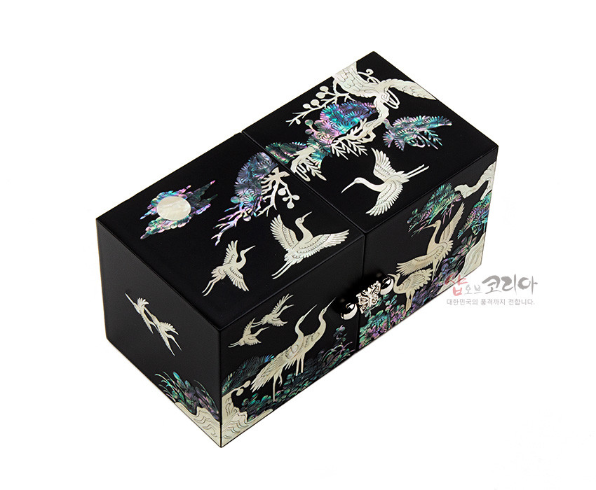 [텍스트: 샵오브코리아 대한민국의 품격까지 전합니다.] 흑색 옻칠 바탕에 자개 상감 기법으로 달과 학, 소나무와 파도 문양을 은은한 오팔빛으로 표현한 금속 잠금장식 쌍합 보관함