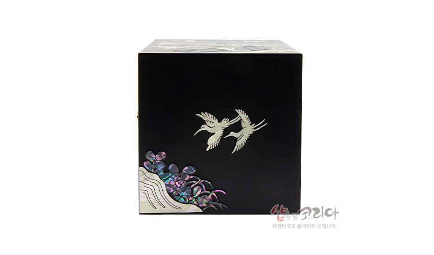 [텍스트: 샵오브코리아 대한민국의 품격까지 전합니다.] 흑색 옻칠 바탕에 자개 상감 기법으로 두 마리 학과 구름, 수풀 문양을 표현한 직사각 쌍합 측면 장식 이미지