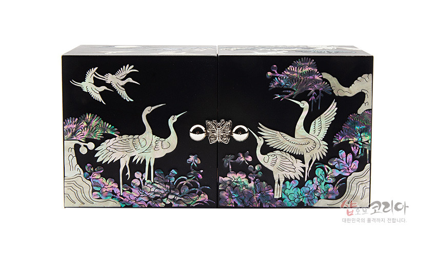 [텍스트: 샵오브코리아 대한민국의 품격까지 전합니다.] 흑색 옻칠 바탕 위 자개 상감으로 학과 소나무, 달빛 풍경을 표현한 금속 잠금장식 쌍합 디자인