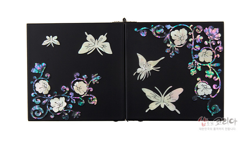[텍스트: 샵오브코리아 대한민국의 품격까지 전합니다] 무광 검정 옻칠 바탕에 자개 상감으로 표현된 나비와 꽃 넝쿨 문양 장식 쌍합 상판 모습