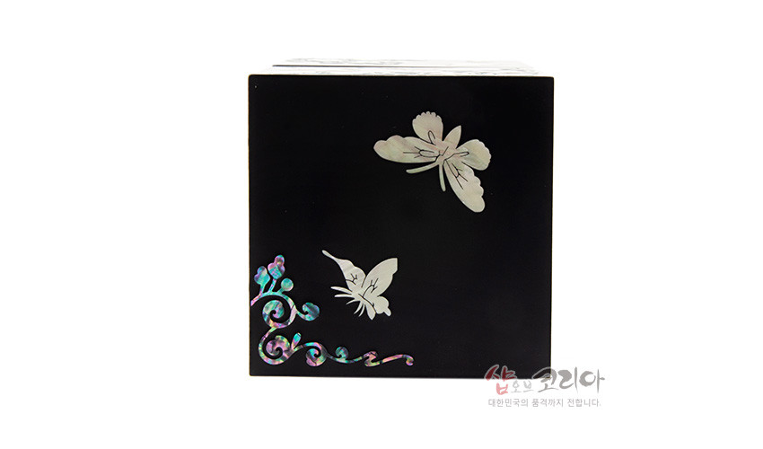 [텍스트: 샵오브코리아 대한민국의 품격까지 전합니다.] 무광 흑색 옻칠면 위에 나비와 꽃 넝쿨 자개 상감이 배치된 직사각 쌍합 측면 장식 모습