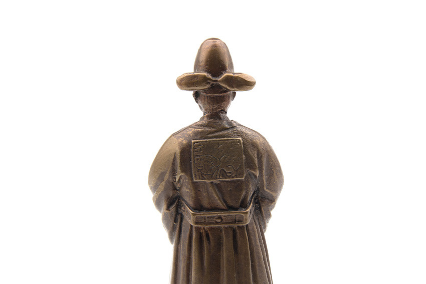 청동 색 금속 재질로 제작된 전통 혼례 신랑 형상의 종, 뒷모에 사각 문양 장식과 매끄러운 광택, 자연스럽게 흐르는 주름 표현이 돋보이는 장식품