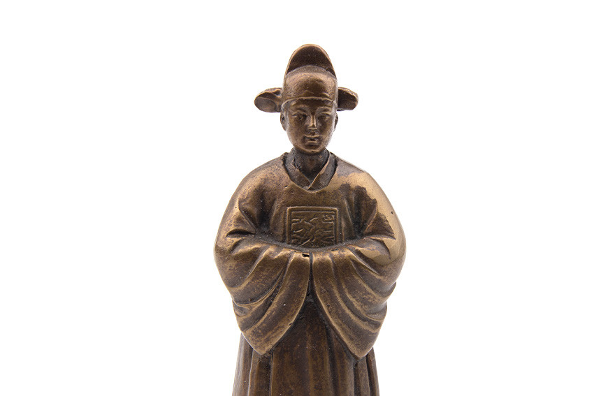 청동 재질로 제작된 전통 혼례 신랑 형상의 장식 종, 가슴의 사각 문양과 소맷부리 주름을 섬세한 조각 기법으로 표현한 청동 공예품