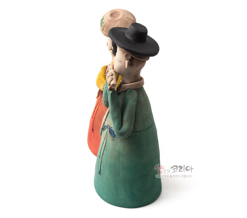 [텍스트: 샵오브코리아 대한민국의 혼과 정까지 전합니다.] 황토로 빚어 저온 소성한 도자기 인형, 녹색 도포와 검은 갓, 붉은 치마와 노랑 저고리의 대비색으로 표현한 선비와 여인 한쌍 형상화 장식품