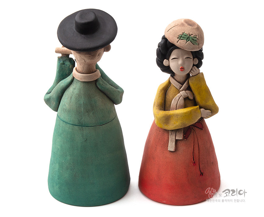 [텍스트: 샵오브코리아 대한민국의 옻·칠기 전문입니다.] 황토를 도자기 기법으로 빚어 채색한 선비와 여인 인형, 녹색과 붉은색 치마·노랑 저고리의 대비와 단순화된 얼굴·머리 장식이 특징인 전통 공예 인형 세트