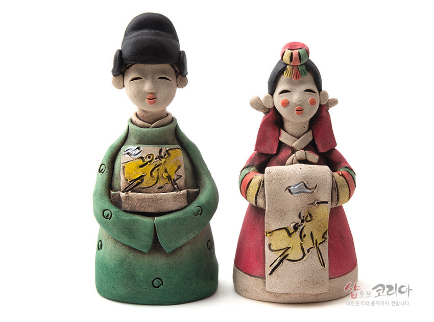 [텍스트: 샵오브코리아 대한민국의 품격까지 전합니다.] 황토 재질 도자기 기법 신랑신부 인형, 녹색·홍색 한복과 황색 동물 문양 패널, 수묵화풍 채색이 돋보이는 전통 혼례 장식 인형