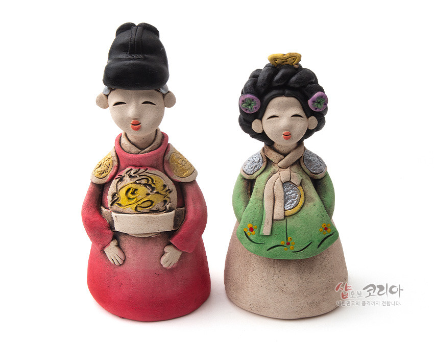 [텍스트: 샵오브코리아 대한민국의 품격까지 전합니다.] 붉은 곤룡포와 녹색 한복 장식의 황토 도자 인형, 용문과 화문 채색으로 표현한 왕과 왕비 전통 조형물