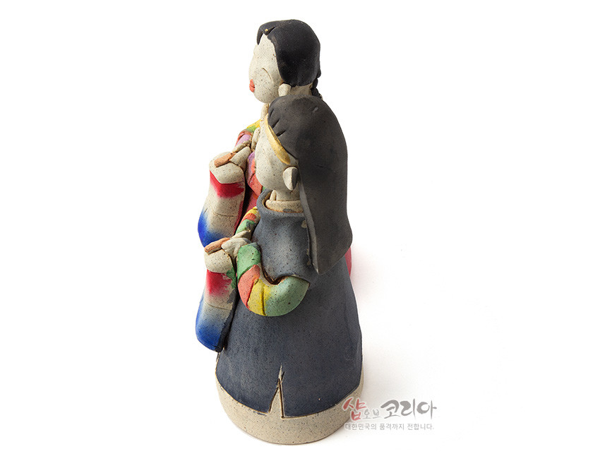 [텍스트: 샵오브코리아 대한민국의 멋과 정까지 전합니다.] 황토 느낌의 거친 도자 재질로 빚은 남녀 전통 인형, 색동 한복 소매와 붉은·파란색 청사초롱을 채색한 소박한 조형미의 장식 인형 모습