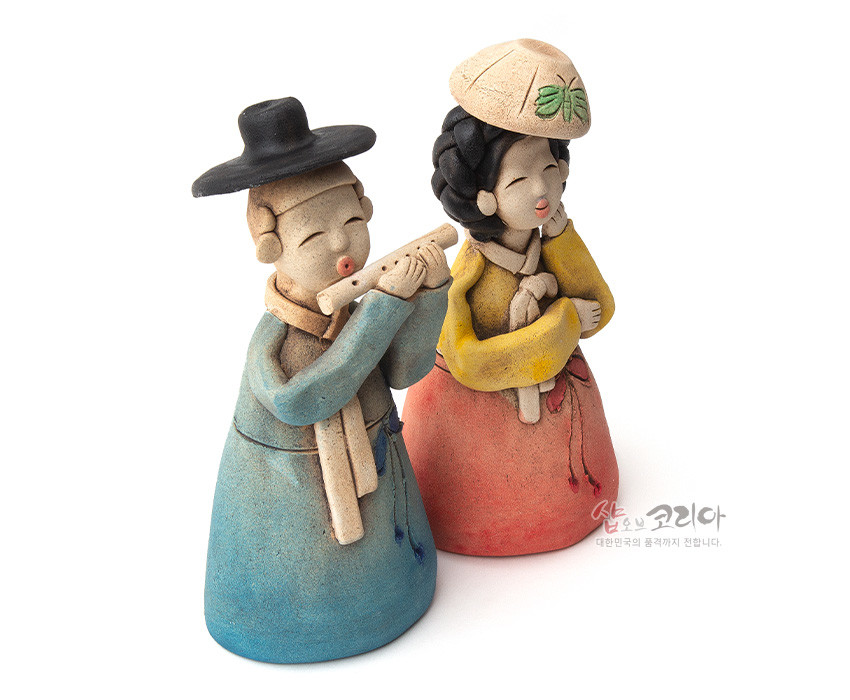 [텍스트: 샵오브코리아 대한민국의 품격까지 전합니다.] 황토를 빚어 구운 도자 인형, 청록·홍토색 한복과 나비 문양 갓, 파스텔톤 채색이 조화를 이룬 선비와 여인 형상 인형 장식