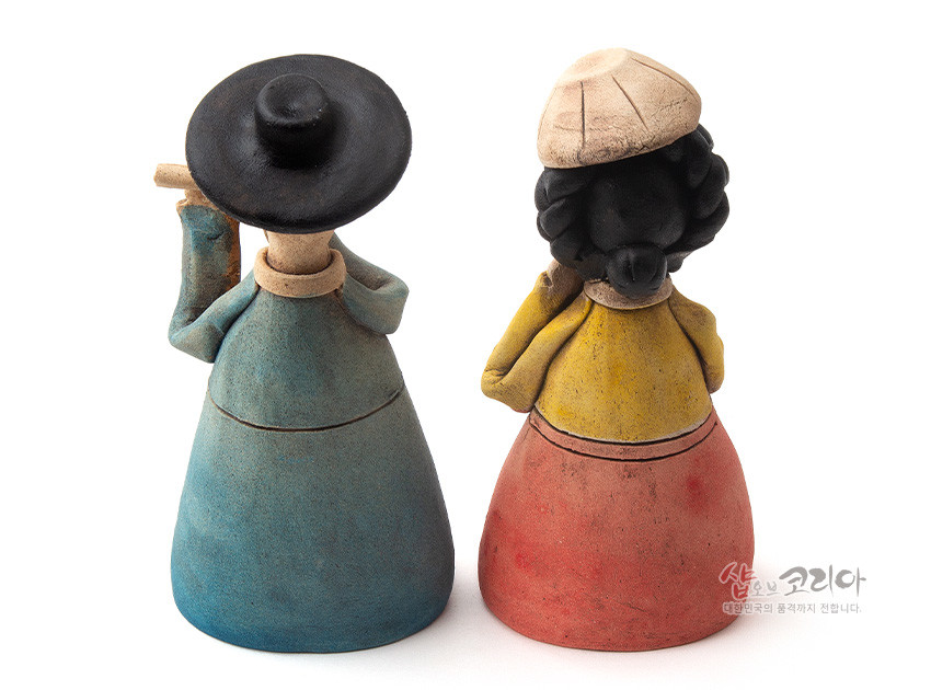 [텍스트: 샵오브코리아 대한민국의 혼과 정까지 전합니다.] 황토 소재로 빚어 저온 소성한 남녀 한복 인형, 청록·황·홍의 파스텔톤 채색과 간략화된 선비 갓·여인 머리 장식이 조화된 도자 조형 장식