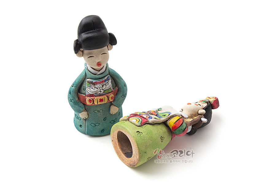 [텍스트: 샵오브코리아 대한민국의 문화를 세계까지 전합니다.] 채색 황토와 도자기 기법으로 만든 신랑신부 인형, 오방색 혼례복과 길상 문양을 수공 채색한 전통 공예품 형상