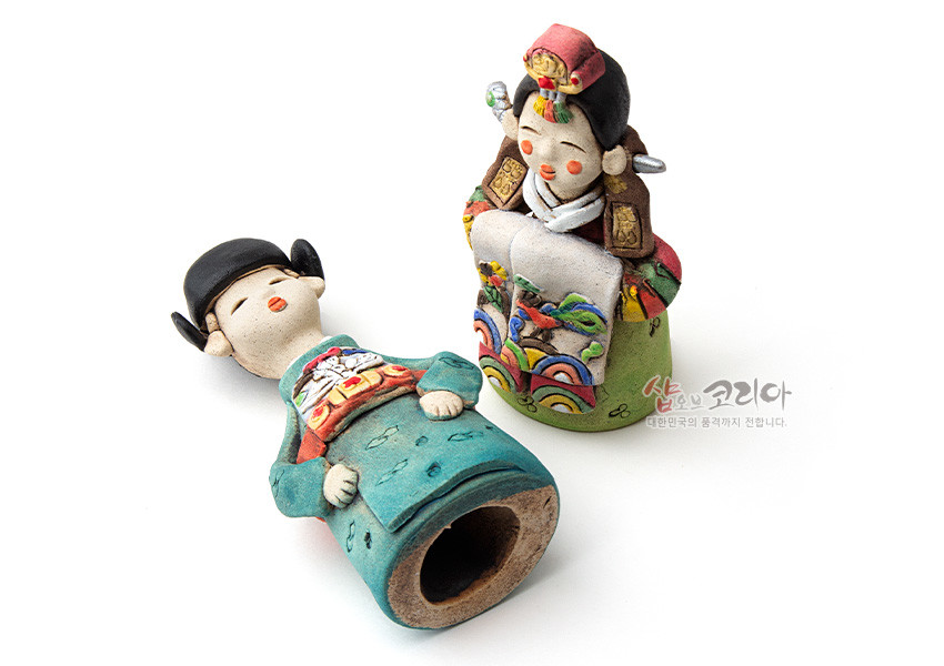 [텍스트: 샵오브코리아 대한민국의 품격까지 전합니다.] 채색 황토 도자기 기법의 전통 혼례 신랑신부 인형, 오방색 무지개·봉황·꽃 문양과 섬세한 수채색 장식 표현