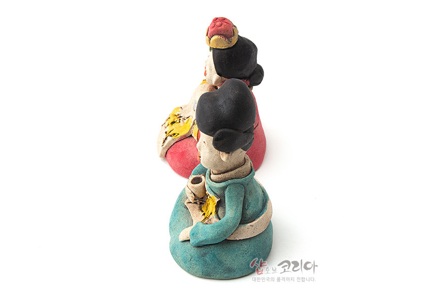 [텍스트: 샵오브코리아 대한민국의 품격까지 전합니다.] 황토 질감의 도자기 기법으로 빚은 전통 혼례 신랑신부 인형, 청록·홍색 한복 채색과 추상적인 노란 문양 장식이 특징인 후면 측면 구성 이미지
