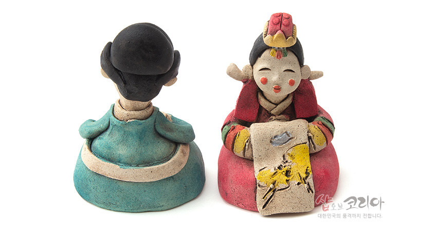 [텍스트: 샵오브코리아 대한민국의 품격까지 전합니다.] 황토 재질 도자기 기법의 혼례 신랑신부 인형, 붉은색·청록색 한복 채색과 노란 수묵화풍 회화문 장식이 조화를 이루는 전통 인형 세트