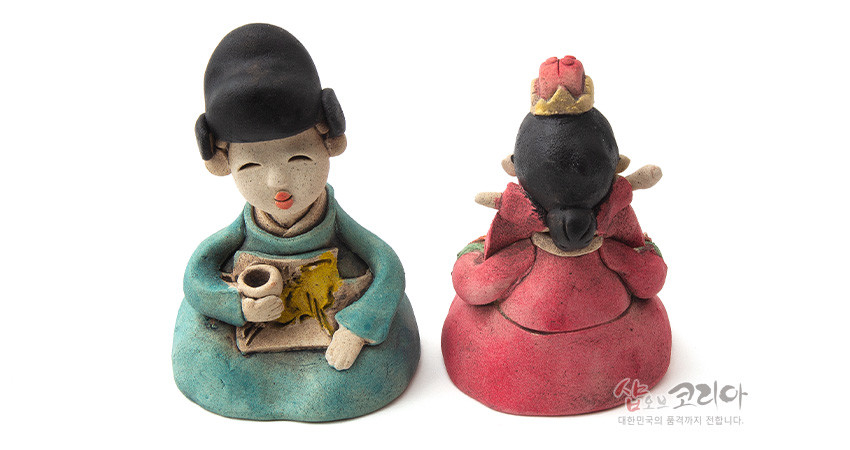 [텍스트: 샵오브코리아 대한민국의 혼을 전세계 전달합니다.] 황토 재질 도자기 기법으로 빚은 전통 혼례 신랑신부 인형, 청록·홍색 한복과 노란 수묵화풍 회화문이 특징인 장식 인형 세트