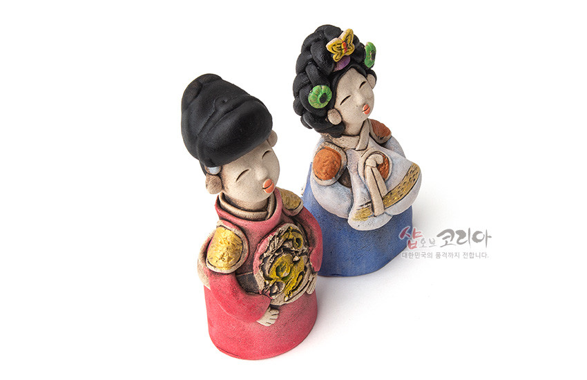 [텍스트: 샵오브코리아 대한민국의 품격까지 전합니다.] 황토 느낌의 도자기 기법으로 만든 왕과 왕비 인형 한 쌍, 붉은색·청색 한복과 금색 용 문양, 입체적인 머리장식이 어우러진 전통 조형물