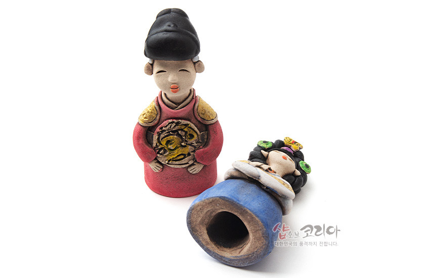 [텍스트: 샵오브코리아 대한민국의 품격까지 전합니다.] 황토를 구워 채색한 도자기 왕과 왕비 인형, 붉은색 곤룡포와 금색 용문·청색 치마와 화려한 머리장식이 돋보이는 전통 조형물