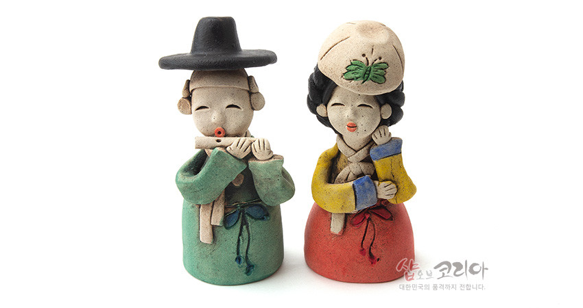 [텍스트: 샵오브코리아 대한민국의 품격까지 전합니다.] 황토 재질 손조각 선비·여인 인형, 녹색·적색 한복과 노랑 저고리, 나비 문양 모자와 수공 채색이 돋보이는 전통 장식 인형 구성