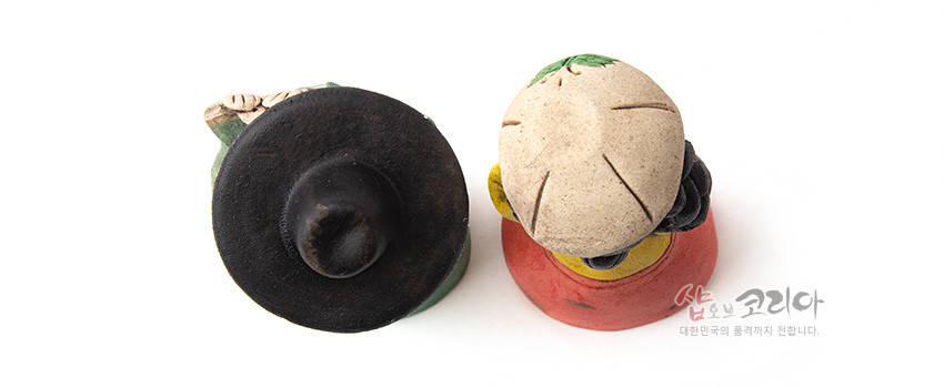 [텍스트: 샵오브코리아 대한민국의 품격까지 전합니다.] 황토 재질로 만든 선비 갓과 여인 머리 모양 인형 상단 클로즈업, 자연 질감과 수공 채색이 돋보이는 전통 조형미 연출