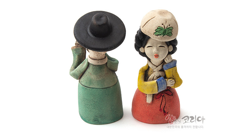 [텍스트: 샵오브코리아 대한민국의 품격까지 전합니다.] 황토 재질 손조각 선비·어우동 인형 한 쌍, 녹색·적색 한복과 노랑 저고리, 나비 자수 문양 모자와 수공 채색이 어우러진 전통 장식 인형 구성