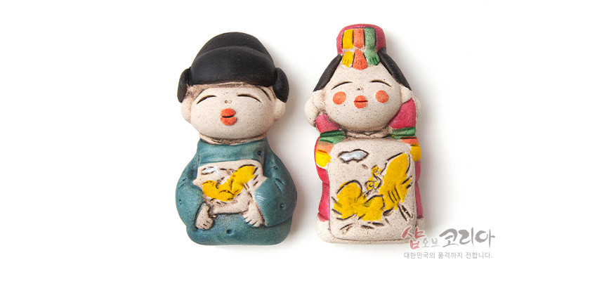 [텍스트: 샵오브코리아 대한민국의 품격까지 전합니다.] 황토 느낌 도자 재질의 신랑신부 자석, 청록·홍색 한복과 노란 나비·새 문양이 채색된 전통 인형 장식