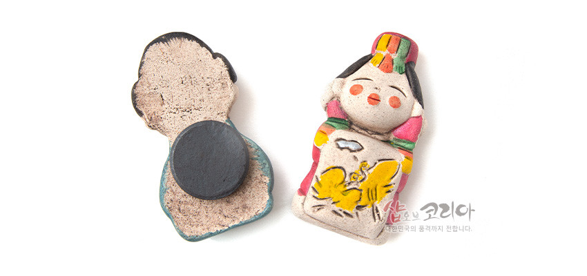 [텍스트: 샵오브코리아 대한민국의 품격까지 전합니다.] 황토 느낌 도자 재질의 신부 인형 자석, 가슴의 노란 나비 문양과 청록·홍색·노랑의 한복 장식이 돋보이는 전통 냉장고 자석 소품