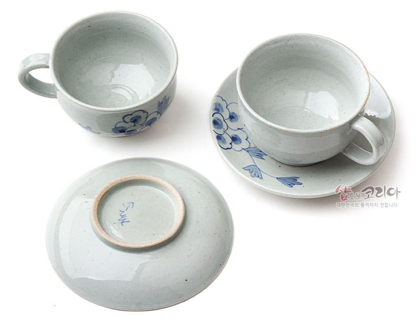 [텍스트: 샵오브코리아 대한민국의 품격까지 전합니다.] 회백색 분청 도자기에 청화 안료로 목단 꽃문양을 수묵화풍으로 그린 커피잔과 받침 2인 세트 구성