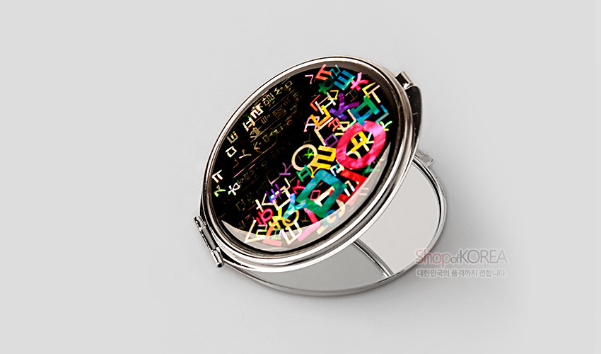 [텍스트: ShopofKOREA 대한민국의 품격까지 전합니다.] 검은 옻칠 바탕 위에 다채로운 색상의 한글 자음도가 자개 느낌으로 장식된 금속 테두리 접이식 손거울 모습