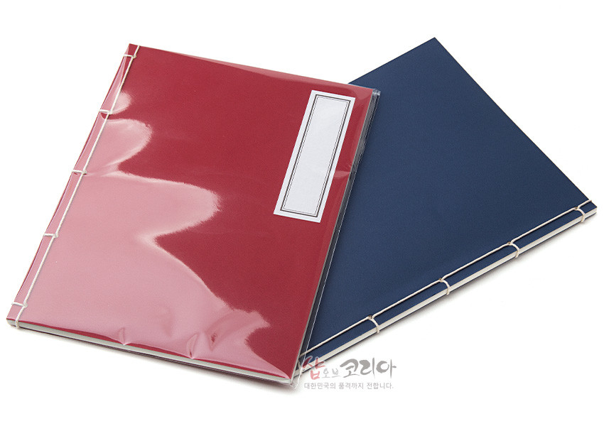[텍스트: 샵오브코리아 대한민국의 품격까지 전합니다.] 붉은색과 남색 종이 표지 위 흰색 실로 오침 제본된 전통 노트, 직사각형 흰 라벨 장식이 포인트인 단정한 디자인 구성