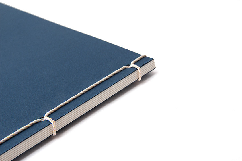 진한 청색 종이 표지에 흰색 실로 다섯 번 노출 제본한 오침 장정 기법의 전통 노트 클로즈업 이미지