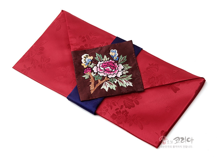 [텍스트: 샵오브코리아 대한민국의 품격까지 전합니다.] 붉은 비단에 꽃문양 자수를 넣은 봉투형 예단보와 짙은 갈색 비단 위 모란·나비 자수 장식, 감색 비단 배색 조화 이미지 설명