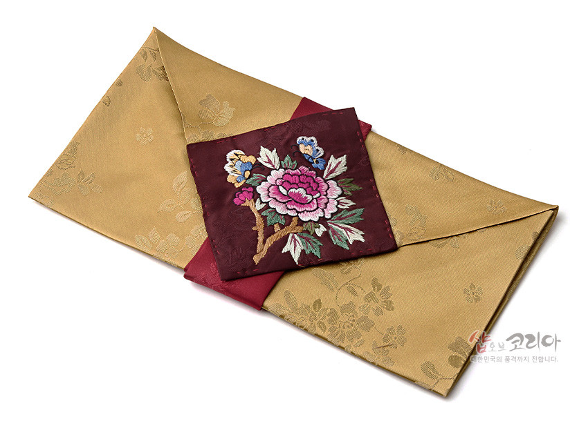 [텍스트: 샵오브코리아 대한민국의 품격까지 전합니다.] 황금색 비단에 꽃문양을 짜넣은 예단보와 자주색 비단 위 화려한 목단·나비 자수 장식의 봉투형 전통 비단봉투 구성