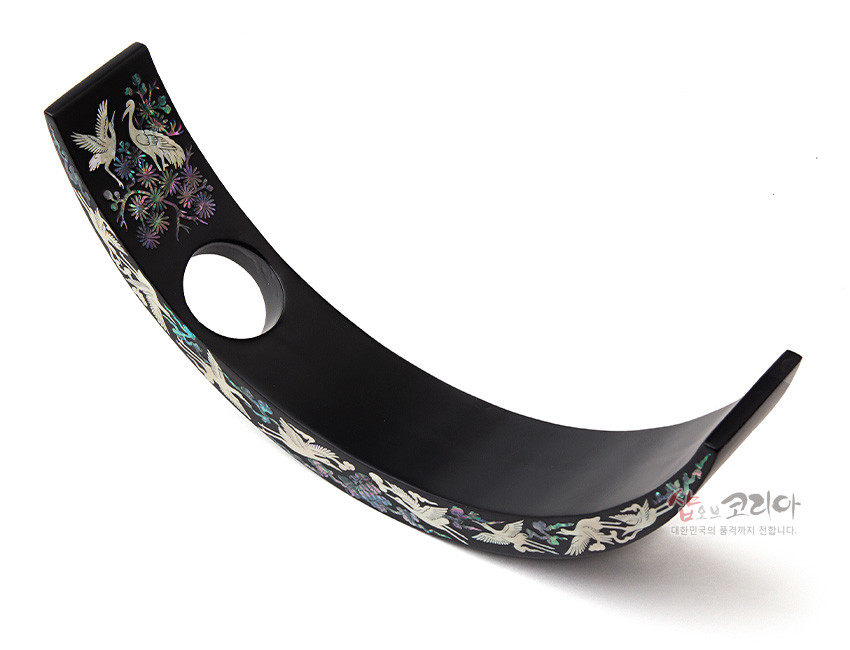[텍스트: 샵오브코리아 대한민국의 품격까지 전합니다.] 무광 흑색 옻칠 곡선형 바디에 자개 상감 기법으로 송학과 꽃 문양을 섬세하게 장식한 나전칠기 와인홀더 이미지 설명