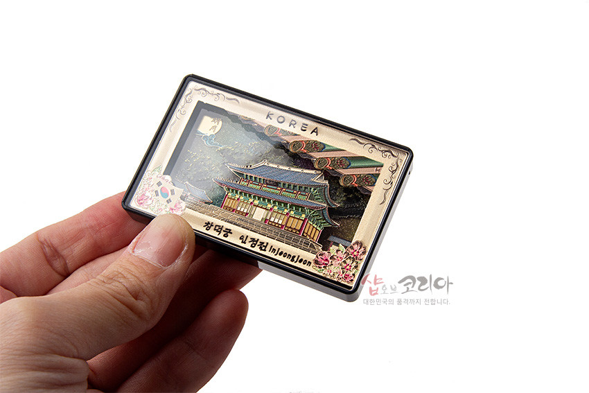 [텍스트: KOREA, 창덕궁 인정전 Injeongjeon] 금속 재질 직사각형 판에 입체 양각 기법으로 표현한 인정전과 단청 문양, 오방색 계열 채색 및 꽃 장식 마그넷 디자인