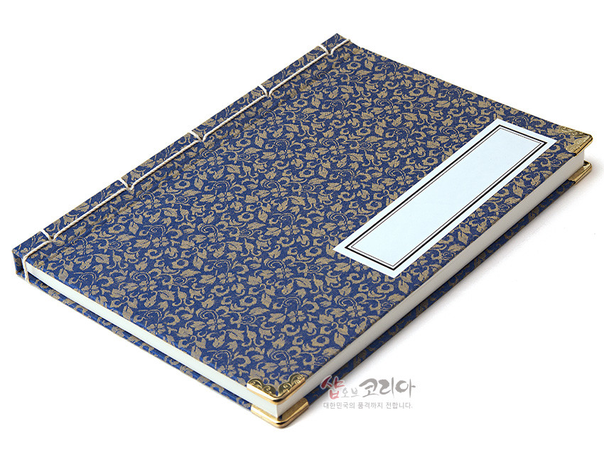 [텍스트: 샵오브코리아 대한민국의 품격까지 전합니다.] 청색 비단에 금색 꽃넝쿨 문양이 직조된 표지와 황동 모서리 장식, 전통 오침 제본법이 어우러진 직사각형 노트 디자인