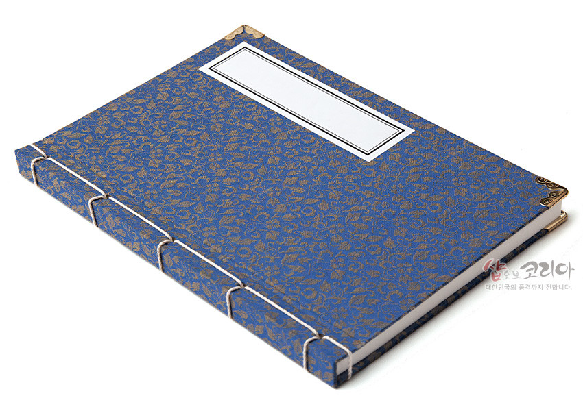 [텍스트: 샵오브코리아 대한민국의 품격까지 전합니다.] 청색 비단 위 금색 꽃무늬 직조 표지와 황동색 모서리 금속 장식, 흰색 실로 엮은 전통 오침 제본 구조의 노트 디자인