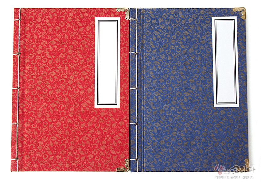 [텍스트: 샵오브코리아 대한민국의 품격까지 전합니다.] 붉은색·청색 비단에 금색 전통 꽃무늬 직조, 금속 모서리 장식과 전통 오침 제본이 어우러진 쌍권 노트 이미지 설명