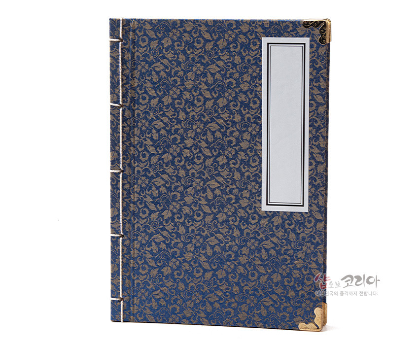 [텍스트: 샵오브코리아 대한민국의 품격까지 전합니다.] 청색 비단에 금색 꽃무늬 직조된 표지와 황동 모서리 금속 장식, 측면 전통 오침 제본이 돋보이는 직사각형 노트 이미지