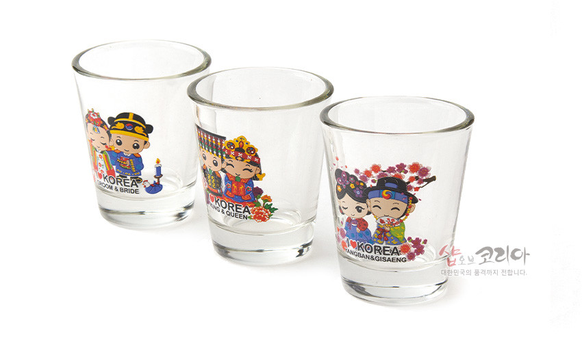[텍스트: KOREA GROOM & BRIDE / KOREA KING & QUEEN / KOREA NOBLEMAN & GISAENG / 샵오브코리아 대한민국의 품격까지 전합니다.] 투명 유리 재질에 한복 차림 커플 캐릭터와 꽃무늬를 다채로운 색상으로 인쇄한 3종 소주잔 세트 이미지 설명