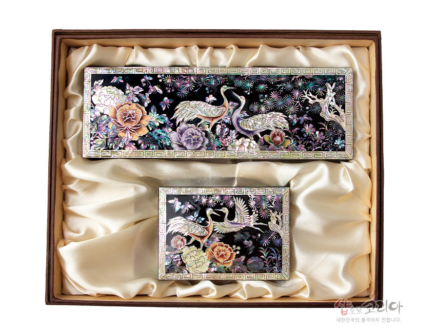 [텍스트: 샵오브코리아 대한민국의 품격까지 전합니다] 흑색 옻칠 바탕 위 자개 상감 기법으로 송학·모란·소나무와 꽃, 구름 문양을 오방색 계열로 장식한 필함·명함함 세트 모습